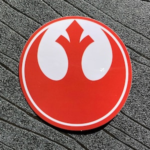 May include: A red and white Rebel Alliance symbol sticker. The symbol is a white starburst with a red background.