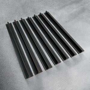 Puede incluir: Una colección de piezas rectangulares negras y ranuradas dispuestas en diagonal sobre una superficie gris. Las piezas tienen un diseño acanalado y están espaciadas uniformemente, creando un patrón. Los objetos parecen estar hechos de un material oscuro y sólido.