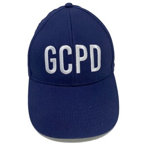 May include: A navy blue baseball cap with white embroidered lettering that reads "GCPD".