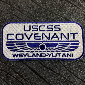 May include: A white embroidered patch with blue lettering that reads "USCSS COVENANT" and "WEYLAND-YUTANI".