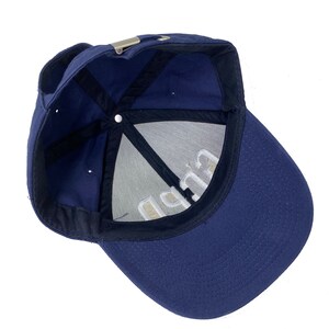 May include: A navy blue baseball cap with a white embroidered logo that says "C.U.P.P."