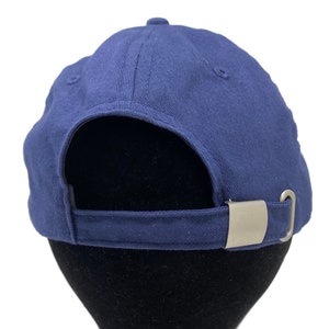 May include: A navy blue baseball cap with a silver metal buckle on the back.