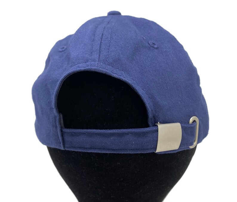 May include: A navy blue baseball cap with a silver metal buckle on the back.