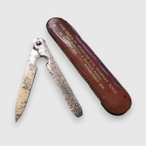 May include: A vintage folding metal tool with a pointed blade and a ruler edge, accompanied by a brown leather case. The case is embossed with the text: CHAS. GRAY & CO. (STAMFORD) LTD, STAMFORD, LINCS. Steel Stockholders & Hardware Factors. ESTABLISHED 1850.