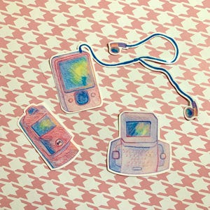 May include: A collection of colorful sticker designs featuring retro-style portable music players and headphones. The stickers have a hand-drawn aesthetic with pastel colors and are set against a pink and white houndstooth pattern.