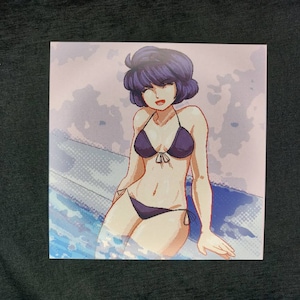 May include: A woman with short, dark blue hair is wearing a black bikini top and bottom. She is sitting in a pool of water with a light blue background.