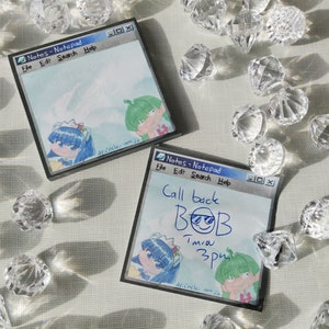 Pode incluir: Duas notas adesivas azuis e brancas com um personagem de desenho animado em cada uma. A nota superior tem o texto "Notes-Notepad" e "File Edit Search Help". A nota inferior tem o texto "Notes-Notepad" e "File Edt Search Help" e o texto escrito à mão "Call back BOB Tmiou 3pm".