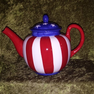 May include: A red, white, and blue teapot with a striped design. The teapot has a blue lid with white stars.