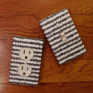 May include: Two white electrical outlet covers with a black and white musical note pattern. One cover has a single light switch with a white toggle.