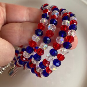 Pu&ograve; includere: Tre braccialetti di perline rosse, bianche e blu con un piccolo ciondolo a forma di bandiera americana.