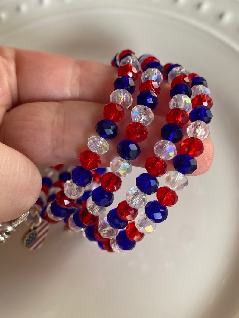 Pu&ograve; includere: Tre braccialetti di perline rosse, bianche e blu con un piccolo ciondolo a forma di bandiera americana.