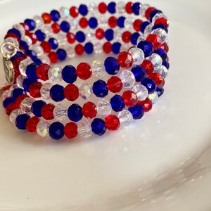 Pu&ograve; includere: Un braccialetto multifilo realizzato con perline rosse, bianche e blu. Il braccialetto &egrave; realizzato con piccole perline sfaccettate ed &egrave; avvolto a spirale.