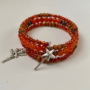 May include: A multi-strand bracelet with orange and brown beads, featuring a silver fairy and star charm.