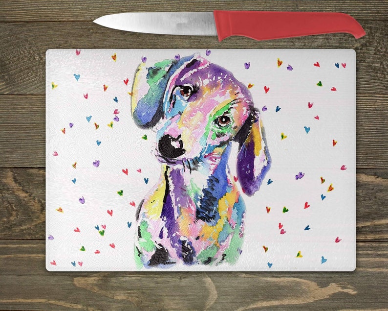 May include: A colorful watercolor painting of a dachshund dog with a white background and scattered hearts in various colors. The dog is looking to the left of the image.