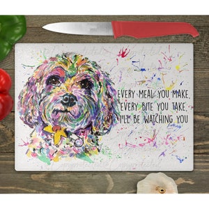 May include: A white cutting board with a colorful watercolor painting of a dog's face. The text "Every meal you make, every bite you take, I'll be watching you" is printed on the board.