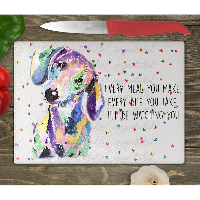 May include: A white glass cutting board with a colorful watercolor painting of a dachshund dog. The text "EVERY MEAL YOU MAKE, EVERY BITE YOU TAKE, I'LL BE WATCHING YOU" is printed on the board.