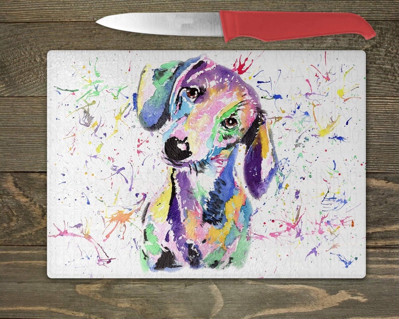 May include: A colorful watercolor painting of a dachshund dog with a white background. The dog is painted in shades of pink, purple, blue, green, and yellow. The background is covered in small, colorful paint splatters.