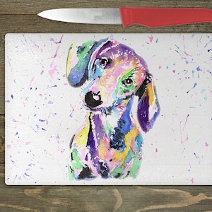 May include: A colorful watercolor painting of a dachshund dog on a white background with colorful paint splatters. The dog is looking to the left of the image.