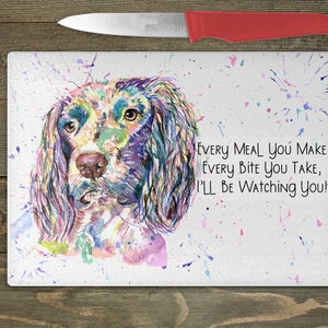May include: A watercolour painting of a dog's head with a colourful background. The dog is looking at the viewer with a playful expression. The text "Every meal you make, every bite you take, I'll be watching you!" is written below the dog.