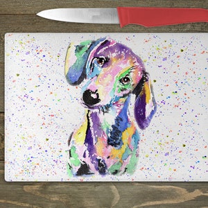 May include: A colorful watercolor painting of a dachshund dog on a white background with a splatter pattern of colorful paint.