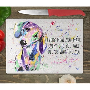 May include: A colorful watercolor painting of a dachshund dog on a white cutting board with the text "EVERY MEAL YOU MAKE. EVERY BITE YOU TAKE, I'LL BE WATCHING YOU."