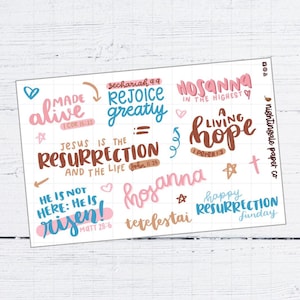 Pu&ograve; includere: Un foglio di adesivi bianco con testo scritto a mano colorato. Le frasi includono "Made Alive", "Rejoice Greatly" e "Jesus is the Resurrection". Le parole sono in rosa, blu e marrone, con elementi decorativi.