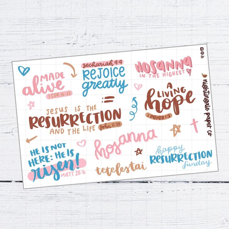 Pu&ograve; includere: Un foglio di adesivi bianco con testo scritto a mano colorato. Le frasi includono "Made Alive", "Rejoice Greatly" e "Jesus is the Resurrection". Le parole sono in rosa, blu e marrone, con elementi decorativi.