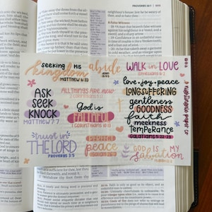 Pu&ograve; includere: Un set di adesivi colorati con versetti biblici su un libro. Gli adesivi presentano frasi come "Seeking His Kingdom" e "Walk in Love" in vari caratteri e colori. Gli adesivi sono progettati per il journaling e l'artigianato religioso.