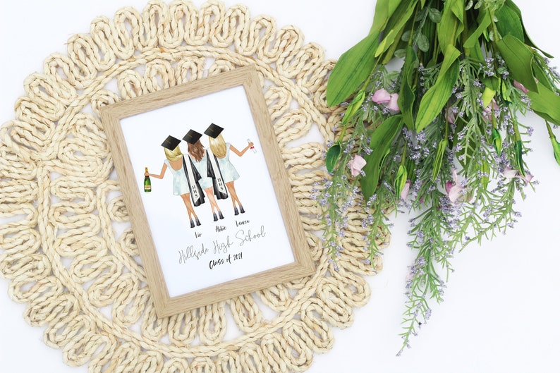 May include: A framed watercolor illustration of three friends in graduation caps and gowns, holding champagne glasses. The text below reads "Hillside High School Class of 2023".