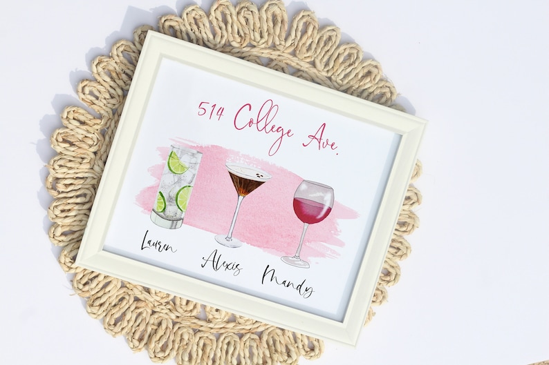 May include: A framed print with a pink watercolor background and three different cocktails. The text "514 College Ave." is at the top of the print. The names "Lauren", "Alexis", and "Mandy" are written below the cocktails.