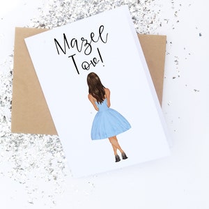 K&ouml;nnte beinhalten: Eine wei&szlig;e Karte mit dem Text "Mazel Tov!" in schwarzer Kursivschrift. Auf der Karte ist eine Comic-Illustration einer Frau in einem hellblauen Kleid und schwarzen Schuhen zu sehen.