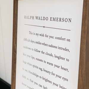 May include: A framed print with a white background and black text. The text is a quote by Ralph Waldo Emerson that reads: "This is my wish for you: comfort on difficult days, smiles when sadness intrudes, rainbows to follow the clouds, laughter to kiss your lips, sunsets to warm your heart, hugs when spirits sag, beauty for your eyes to see, friendships to brighten your being, faith so that you can believe, know yourself."
