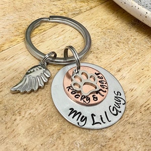 May include: Silver keychain with a small angel wing charm and a round charm with the text "Rocky & Tiger" and "My Lil Guys". The charm is two-toned with a copper center.