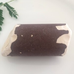 Könnte beinhalten: Ein brauner und weißer Keramik-Holzblock mit rauer Textur. Der Holzblock ist zylinderförmig mit einer leicht unregelmäßigen Form.