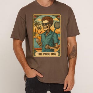 Könnte beinhalten: Braunes T-Shirt mit einem Retro-Grafikdesign eines Skeletts mit Sonnenbrille, das einen Cocktail und einen Poolkescher hält. Die Grafik ist mit dem Text "THE POOL BOY" umrahmt. Der Hintergrund zeigt eine tropische Szene.