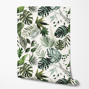 May include: A roll of wallpaper featuring a repeating pattern of green tropical leaves on a white background. The leaves vary in size and shape, including monstera, fern, and palm fronds. The wallpaper is partially unrolled, revealing the pattern.