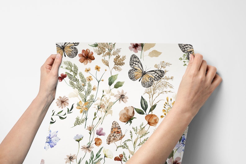 K&ouml;nnte beinhalten: Ein wei&szlig;er Hintergrund mit einem sich wiederholenden Muster aus Aquarell-Schmetterlingen und Blumen in Braun-, Gelb-, Gr&uuml;n- und Blaut&ouml;nen.