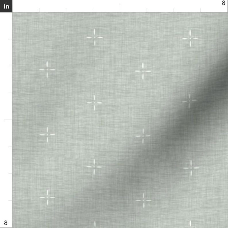 May include: Light gray fabric with a subtle texture and a repeating pattern of small white cross shapes. The fabric appears to be a woven material, suitable for various crafting or sewing projects. The image shows a section of the fabric, approximately 8 inches by 8 inches.
