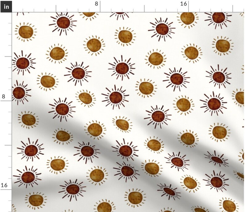 May include: A white fabric with a repeating pattern of brown and gold suns. The suns have a simple, hand-drawn style with radiating lines.