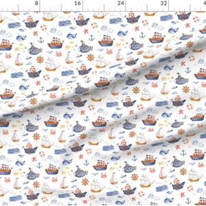 May include: A white fabric with a repeating pattern of watercolor illustrations of blue and red sailboats, yellow anchors, red starfish, blue whales, brown crabs, and yellow life preservers. The pattern is on a white background.