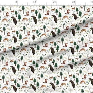 May include: A white fabric with a repeating pattern of brown bears, deer, and pine trees. The pattern is set against a white background with green leaves and brown branches.