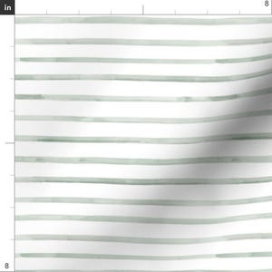 May include: White fabric with horizontal, hand-painted, sage green stripes. The stripes vary in width and have a watercolor effect, creating a soft, textured appearance. The design is simple and modern, suitable for various craft projects.