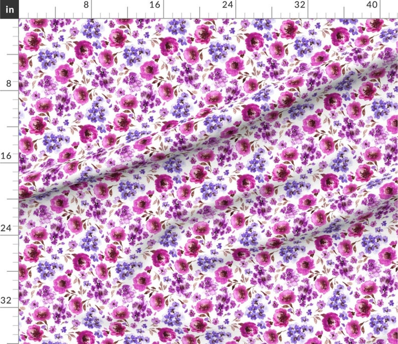 Op de afbeelding: Een witte stof met een herhalend patroon van roze en paarse aquarelbloemen. De bloemen zijn willekeurig gerangschikt en omgeven door groene bladeren.