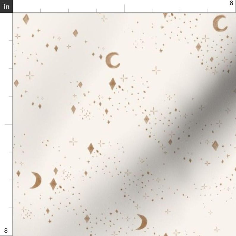 May include: Off-white fabric with a celestial pattern featuring gold crescent moons, diamond shapes, starbursts, and tiny dots. The design is evenly distributed across the fabric, creating a dreamy, whimsical aesthetic. The fabric is 8 inches wide.