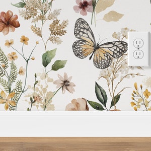 K&ouml;nnte beinhalten: Eine wei&szlig;e Wand mit einer floralen Tapete mit Schmetterlingen, Bl&auml;ttern und Blumen in Braun-, Gelb- und Rosat&ouml;nen. Eine wei&szlig;e Steckdose ist an der Wand sichtbar.