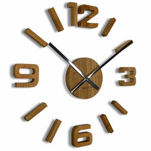 May include: A modern wall clock with a wooden face and floating wooden numbers. The clock hands are black, and the numbers are in a light brown color. The clock face has the text "FLEXISTYLE" printed on it.