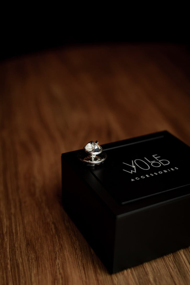 May include: A silver tie tack in a black box with the text "WOLF ACCESSORIES" on the lid.