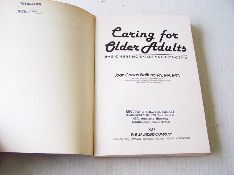 May include: Open book titled "Caring for Older Adults" with text about basic nursing skills and concepts. The author is Joan Carson Breitung. Published by W.B. Saunders Company in 1987. The book is from the Augusta R. Kolwyck Library.