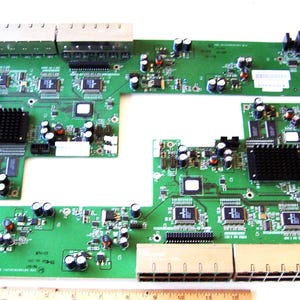 May include: Several green circuit boards with various electronic components, including chips, capacitors, and black heat sinks. The boards have multiple ports and connectors, and some text is visible. A ruler is at the bottom.