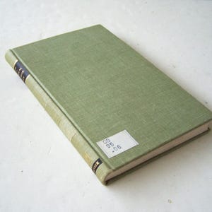 May include: A hardcover book with a light green cover and a white label with black text. The spine has black and gold lettering. The book is closed and resting on a white surface.